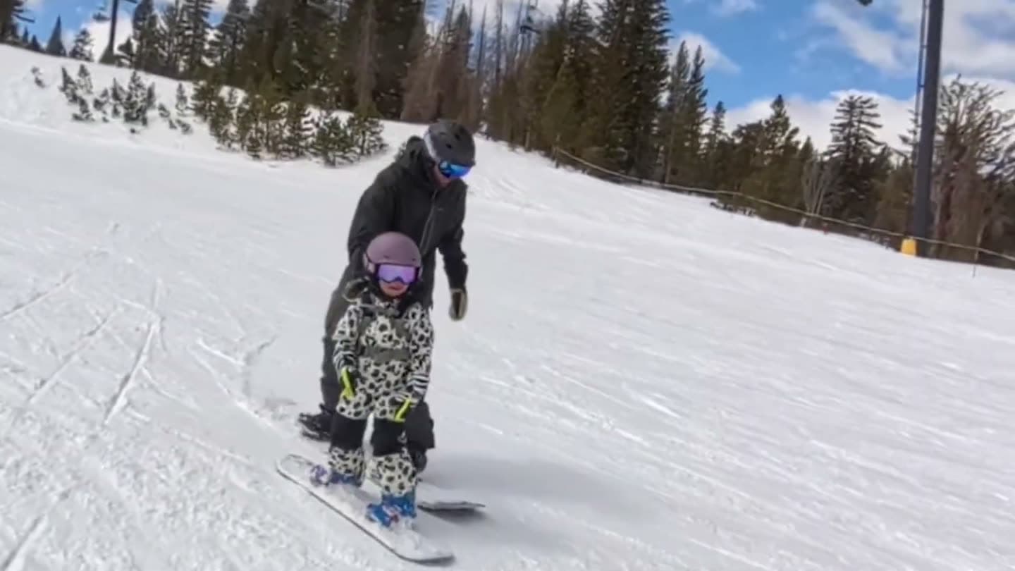 Parent guiding a toddler through a wide S-turn on a beginner run